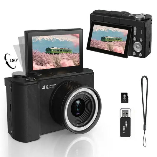 Black compact mirrorless camera with a 180-degree flip-out screen, shown with a lens, USB flash, memory card, and wrist strap on a white background.